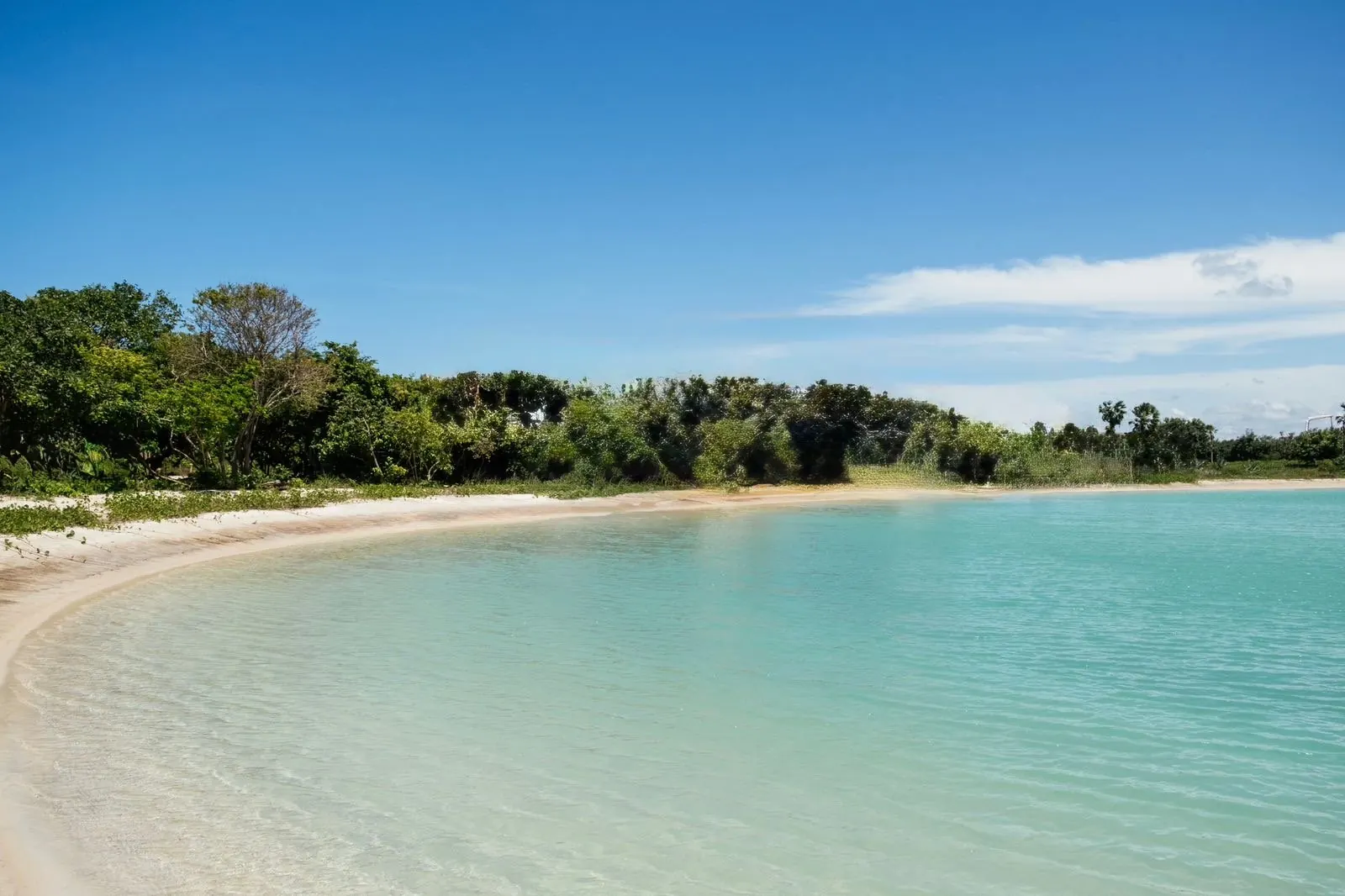 A turquoise lagoon cove under a blue sky