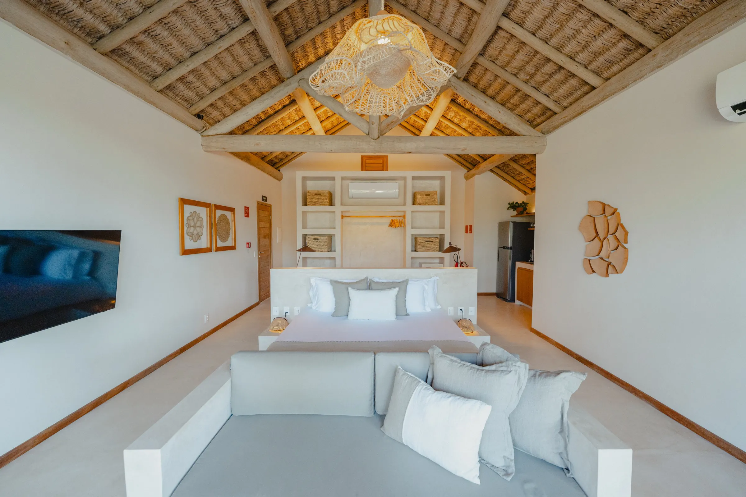 A bright suite with a timber ceiling and a double bed
